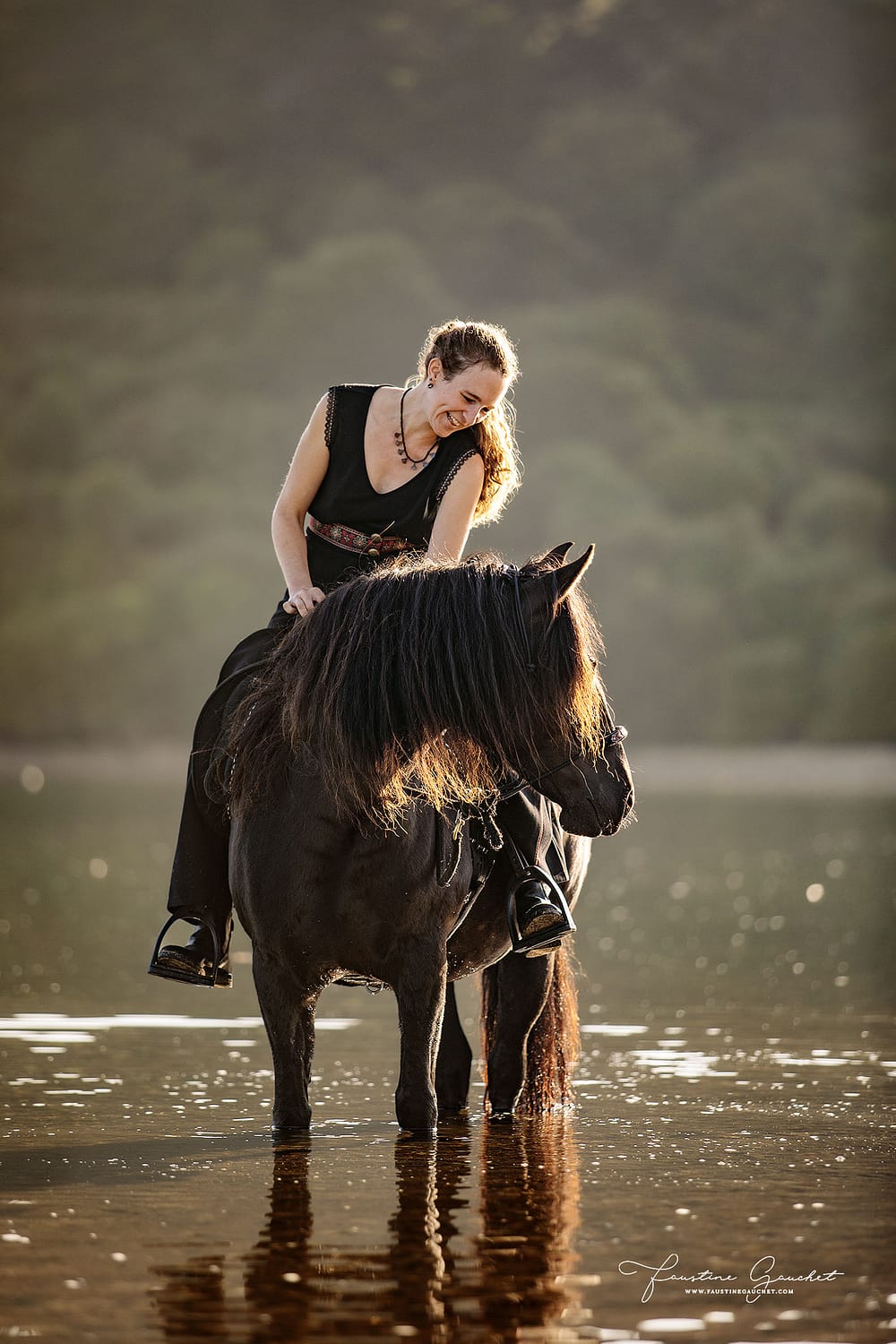 portrait d'une cavalière et sa jument merens noire dans l'eau en bretagne